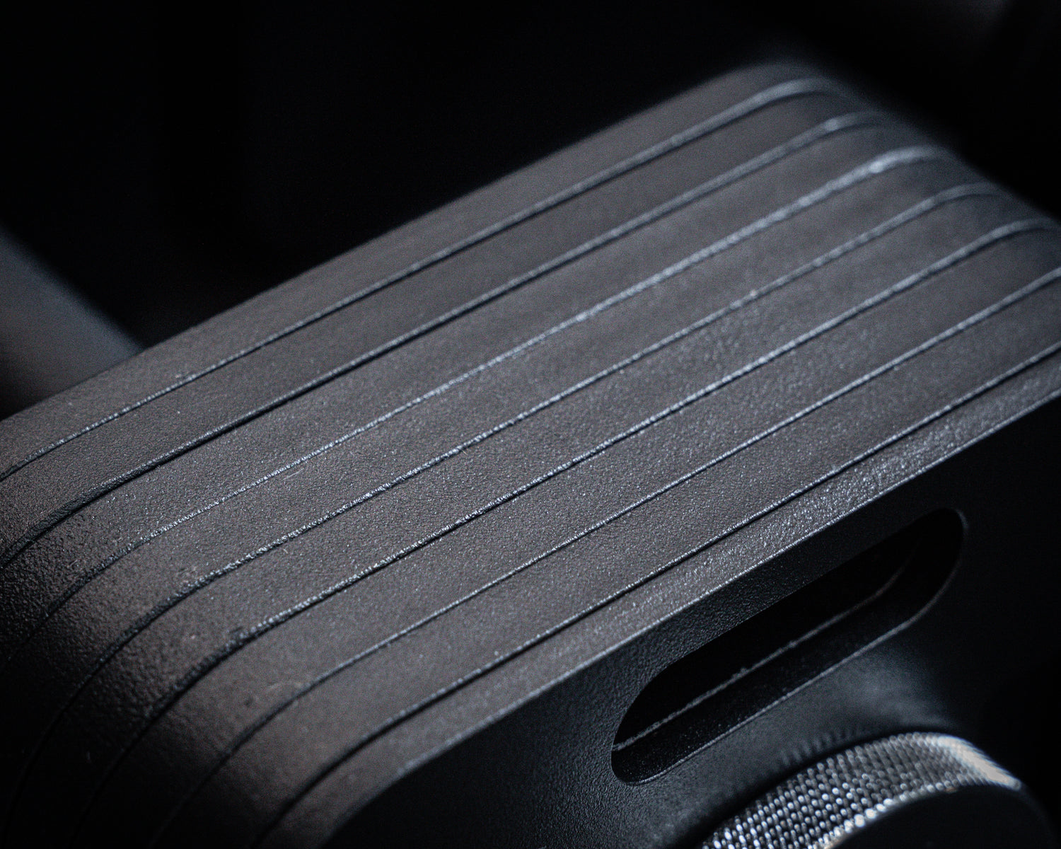 Closeup of black adjustable dumbbell block with smooth matte ridged surface.