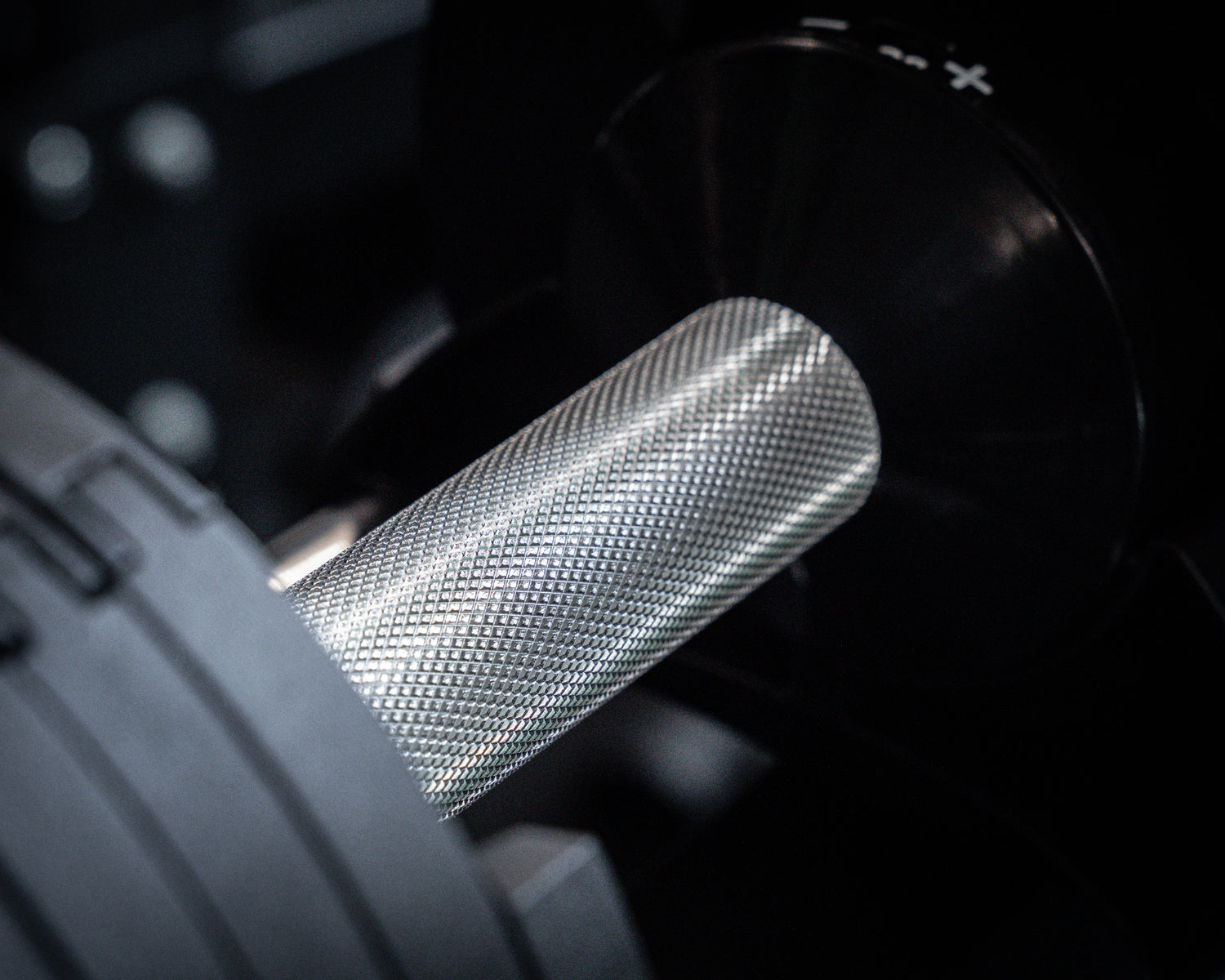Closeup silver knurled dumbbell handle with diamond textured grip.